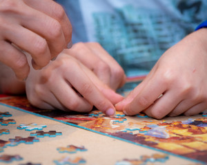 Fototapeta premium Adult and child solving a jigsaw puzzle on a table. 