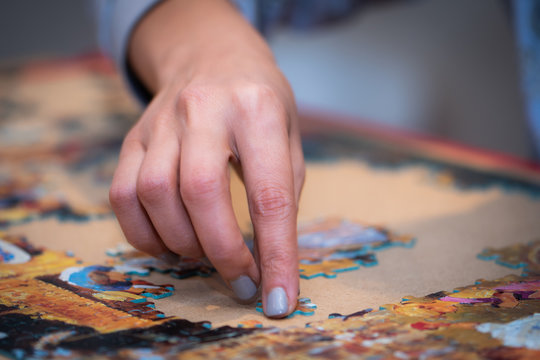 Adult And Child Solving A Jigsaw Puzzle On A Table. 