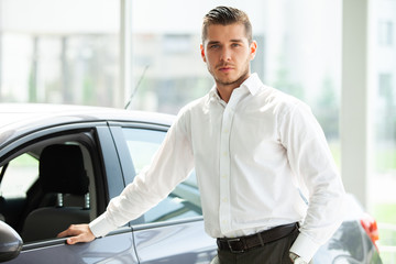 Happy car owner is showing thumbs up and his new car key.