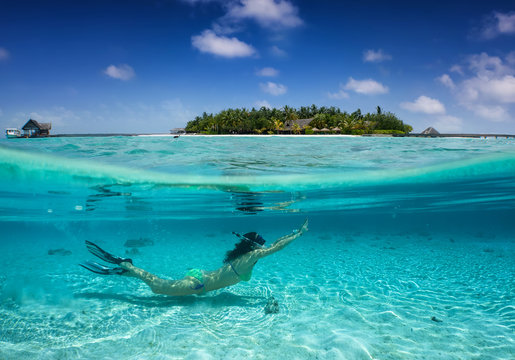 Sommerurlaubs Konzept : Frau im Bikini taucht in klaren, exotischen Gewässern vor einer tropischen Insel; Splitaufnahme