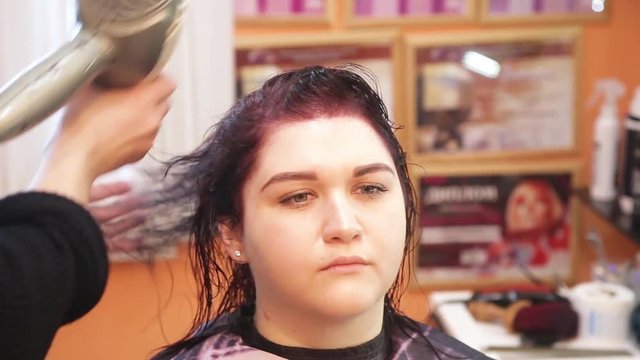 hairdresser's hand blow-dried a girl's hair on a chair