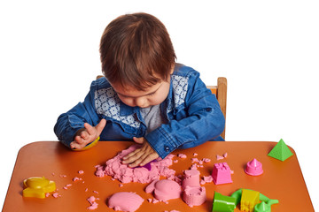 Emotional little child girl playing with kinetic sand on the orange table. Isolated white background