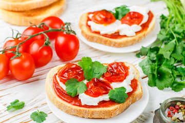 Fresh homemade crispy bruschetta with baked tomatoes cherry, cream cheese (ricotta), red sauce and parsley (cilantro). Crostini, Toast, antipasti, canapes. Healthy gourmet Breakfast. Selective focus