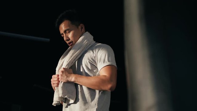 Muscular asian man with a towel. Caring for your body after a hard workout. athlete in dressing room. Chinesse korean boxer after training serious tired