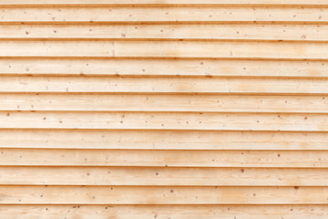 Large wall of light, yellow clean boards. Fragment of the facade of the building sheathed with boards in 