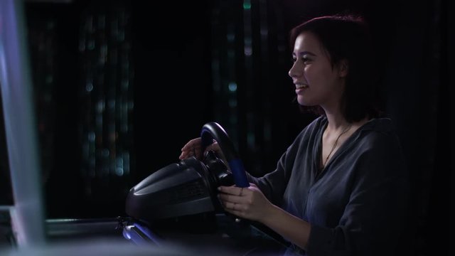 beautiful young woman playing a game with a racing wheel