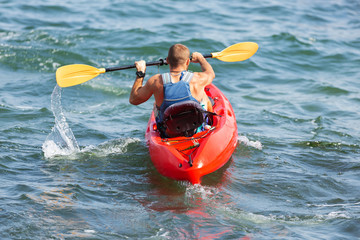 man swims in a red kayak, paddles, splash of water, concept