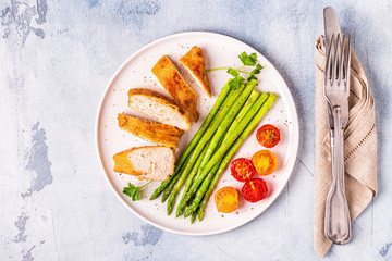 Roasted chicken breast with asparagus and tomatoes.