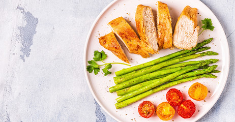 Roasted chicken breast with asparagus and tomatoes.