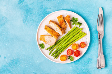 Roasted chicken breast with asparagus and tomatoes.