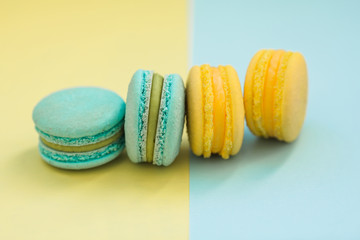 Colorful french macarons on blue and yellow background. Top view. Pastel colors.Concepts about decoration, food background. flat lay