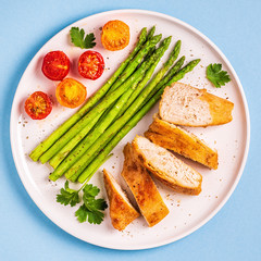 Roasted chicken breast with asparagus and tomatoes.