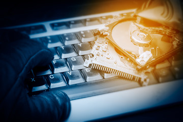 hacker hand on a keyboard. hacked computer hard drive, cybercrime concept