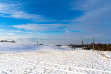 Fototapeta na wymiar Empty Countryside Landscape in Sunny Winter Day with Snow Covering the Ground with Power Lines in Frame, Abstract Background with Deep Look