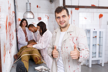 Cheerful guy in quest room with bloody traces