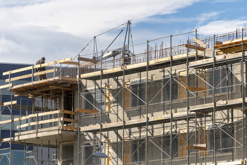 Skilled man standing on scaffolding near incomplete building