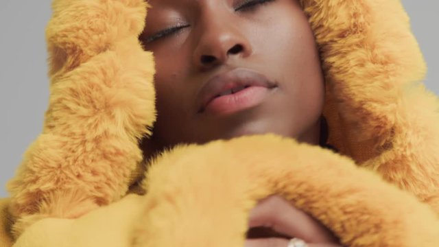 macro shoot of mixed race woman wear yellow hood with fur, and wrap up on it