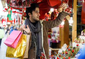 Happy young man with Christmas toys at fair outdoor