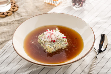 Summer cold soup okroshka with radish, cucumber and dill served on table