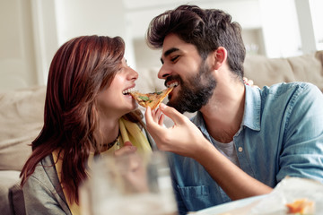 Young couple eating pizza at home