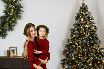 beautiful family, mother and daughter in red dresses on the eve of the new year and Christmas