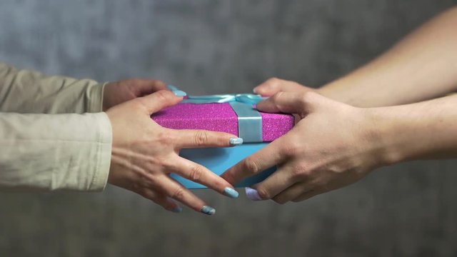 men's hands pass into the women's hands a gift blue box with a red lid