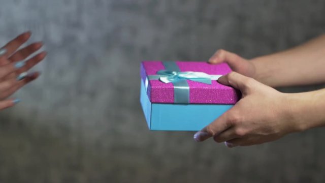 men's hands pass into the women's hands a gift blue box with a red lid