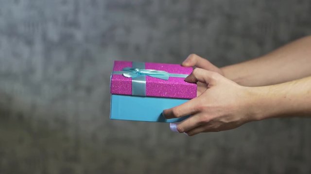 men's hands give a girl a gift in a beautiful box but then do not give it away