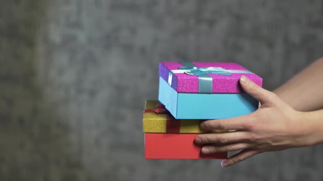 men's hands give the girl two gifts in beautiful boxes