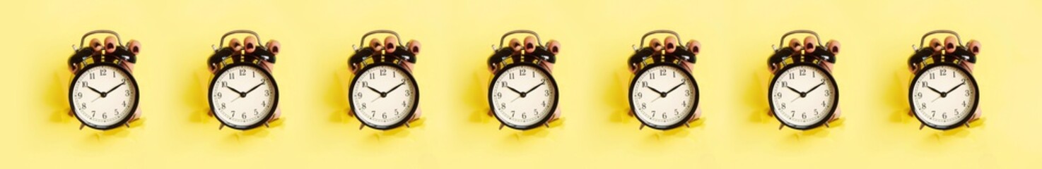 Seamless pattern of hands holding black alarm clock through hole in yellow paper background. Wake up alert concept. Morning routine. Minimalist style design.