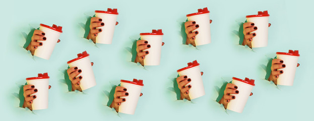 Chaotic pattern of female hand holding white paper mug on blue background. Take away coffee cup concept. Mock up with copy space