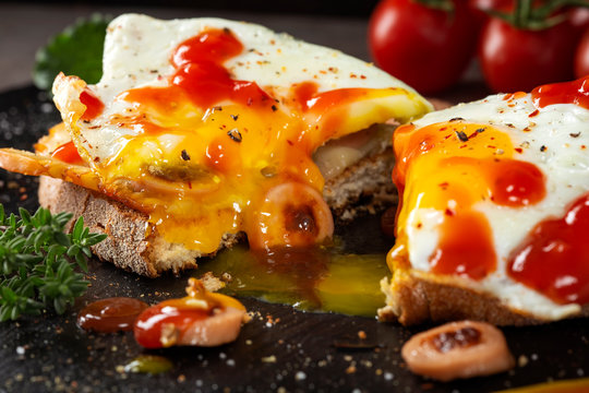 Open sandwich made with egg, cheese and sausages on slate with ketchup