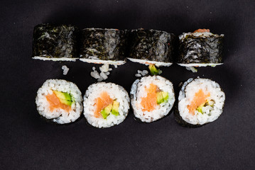 sushi with salmon and avocado on the black background
