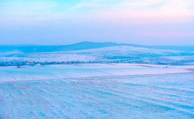Sunset over hills covered with snow