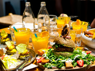 Lunch with fresh avocado tasty burger with lettuce, strawberry, sweet potatoes and fresh orange juice