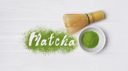 Lettering from green matcha tea with bamboo whisk on white wood