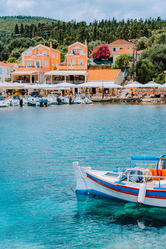 Traditional colorful Greek fishing boat in front of picturesque village, Greece