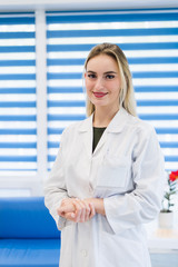 Young female doctor or nurse standing at hospital reception