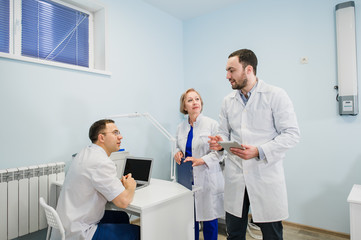 Fototapeta premium Medical staff discussing over medical reports using laptop and tablet pc. Healthcare professionals having discussion in hospital office.