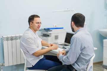 Obraz premium Male doctor discussing reports with patient at desk in medical office
