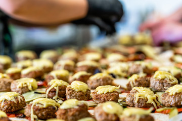 Female Chef Putting Ingredients of Burgers on a Sliced Bread Spread on a Table in Black Gloves - Concept of the Hard Working Person and the Hygiene in the Kitchen