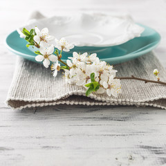 Fototapeta na wymiar Spring table set with plates and white flowers
