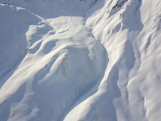 Aerial view of snow covered terrain in mountain area. Mountains in central Switzerland. Alps with snow in beautiful light with shadow and sun.