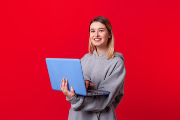 Pretty smiling young woman holding laptop and looking at camera