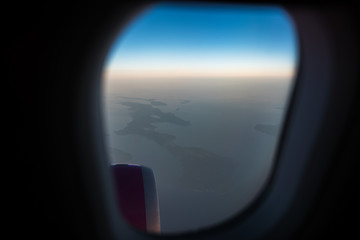 Naklejka premium View from the window to airplane engine. Above the sky, on sunrise.