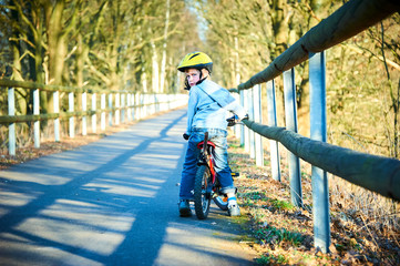 Obraz premium Boy riding his bike on a spring country track. Road concept for safety and child development