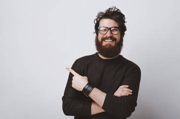 Stylish hipster model in glasses is pointing at  copy  space with crossed hands