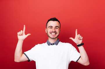 Fototapeta premium Handsome young boy in white tshrit pointing up at copy space