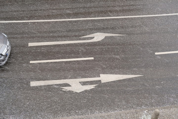 Road with road signs in the snowfall and approaching car