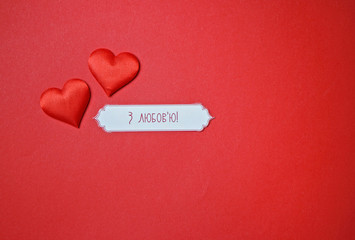 Two red hearts for Valentine's Day love on a red paper background